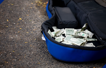 Picture of a blue guitar case filled with money.