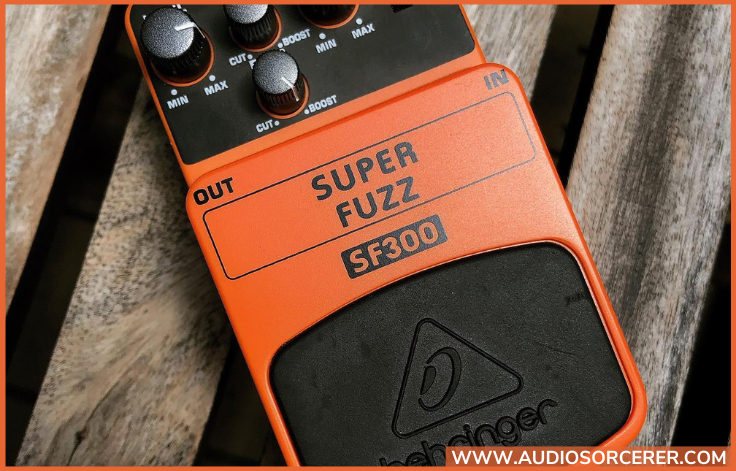 Behringer SF300 Super Fuzz Pedal laying on wood plank flooring.