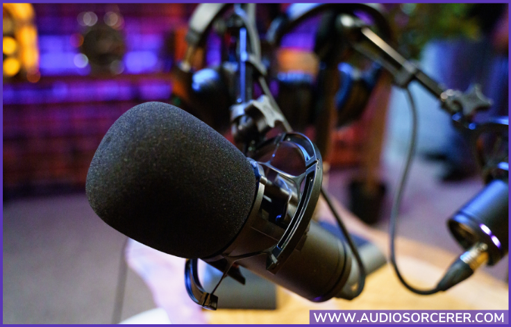 Microphone on a stand with a foam pop filter on it in a podcast studio.