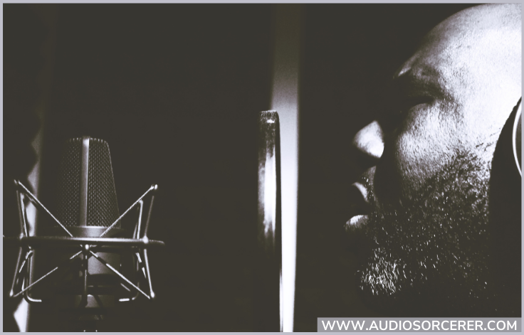 A man singing into a microphone and pop filter in a recording studio.