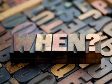 The word "when?" carved into a wooden block with other letters behind it.