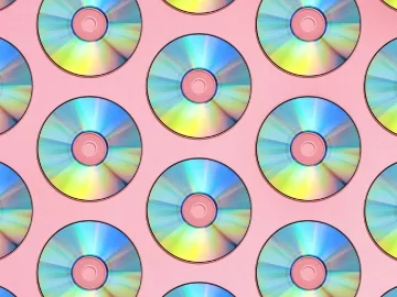 A bunch of CDs with a pink background.