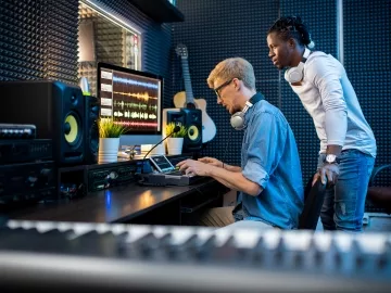 Two guys in a recording studio creating music in front of a computer.