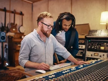 An image of a music producer working in a studio, demonstrating what does a music producer do while collaborating with artists and creating music.