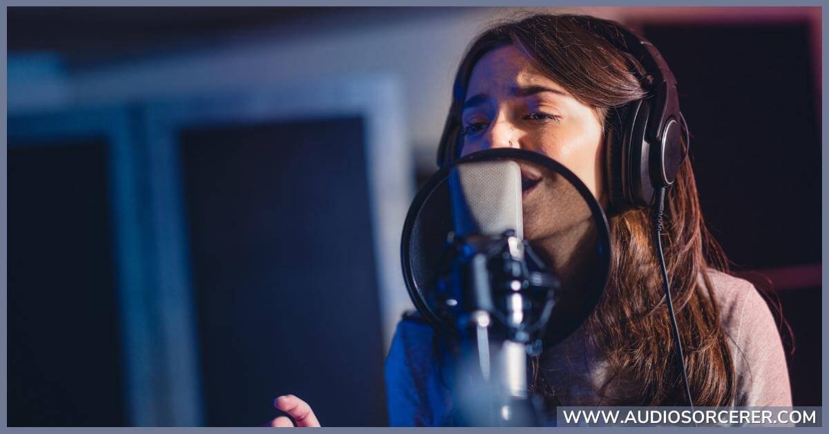 Woman recording vocals in a studio using a large diaphragm condenser mic with a pop filter in front of it.