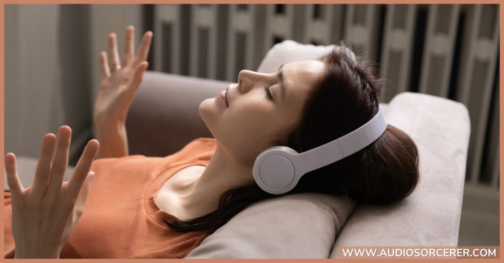 Lady listening to music on her couch with white headphones.