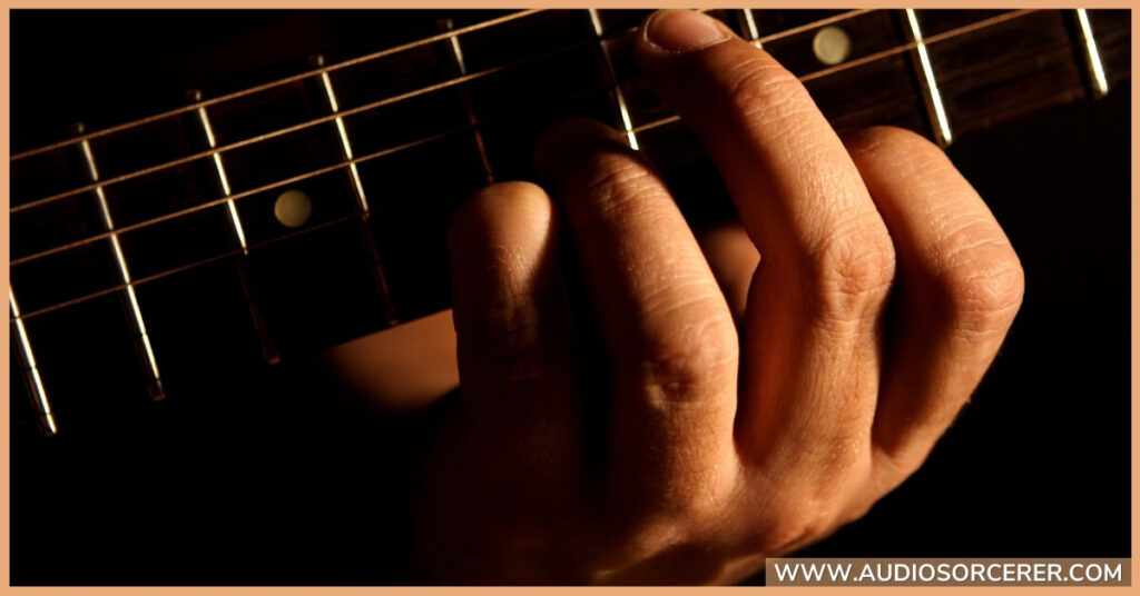Closeup of a man playing a chord on a acoustic guitar.