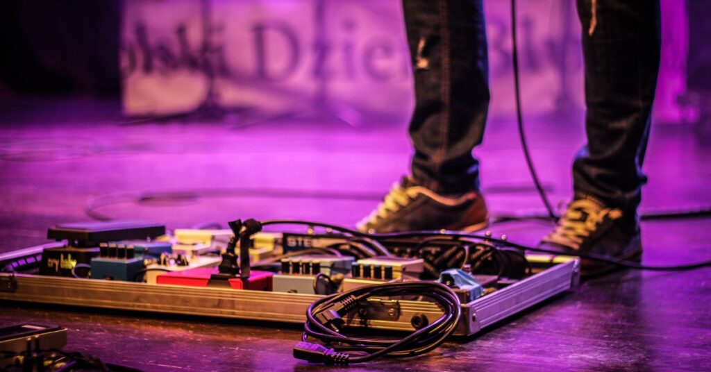 Guitarist with a pedalboard on stage.